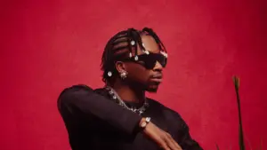 Afrobeats singer Oxlade performing live on stage while promoting his sophomore album OXNB, surrounded by lights and cheering fans.